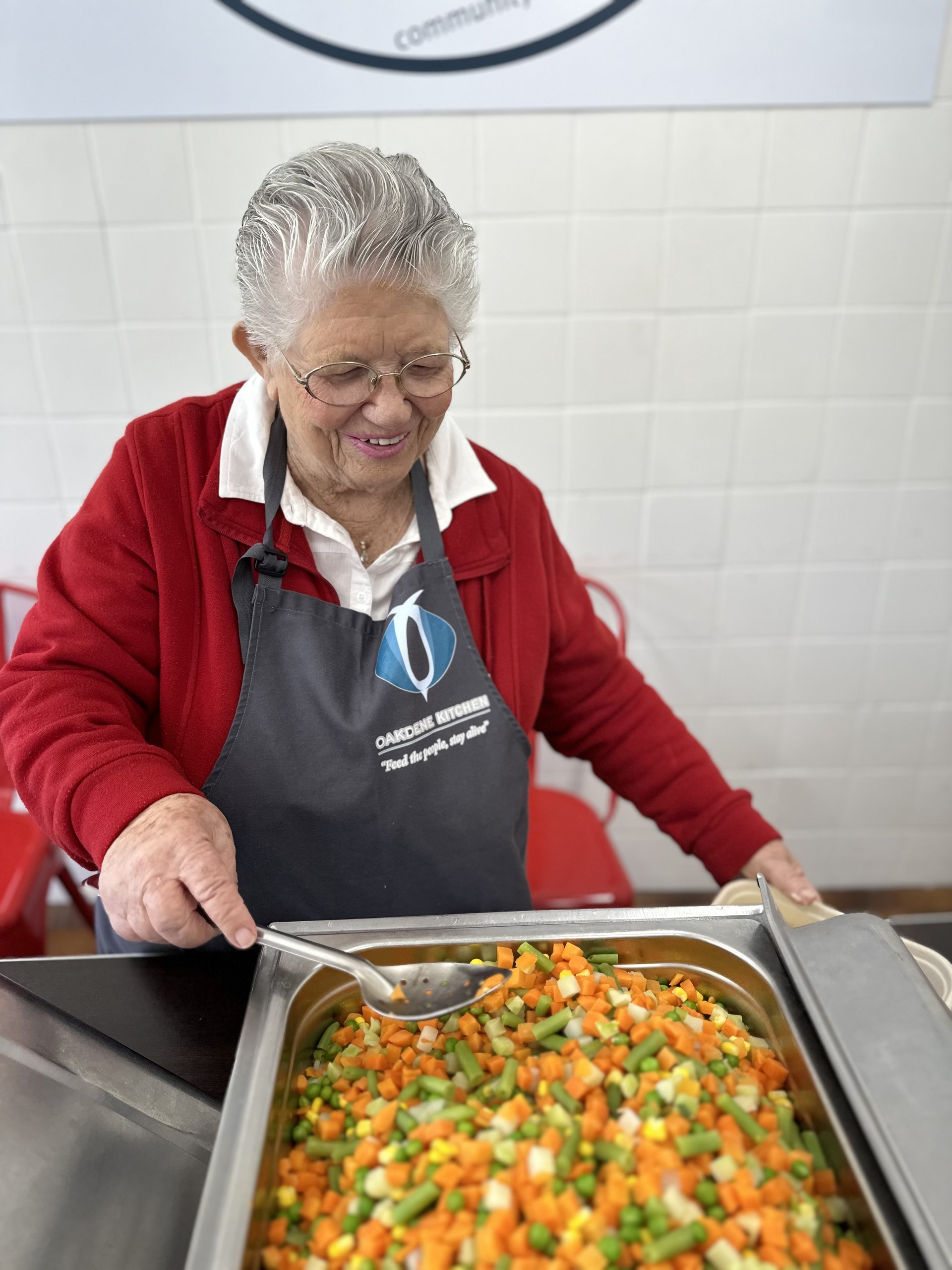 Smiling volunteer serving food at Oakdene Kitchen